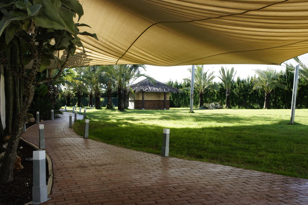 Jardín del albergue con toldos de sombra y zona de descanso