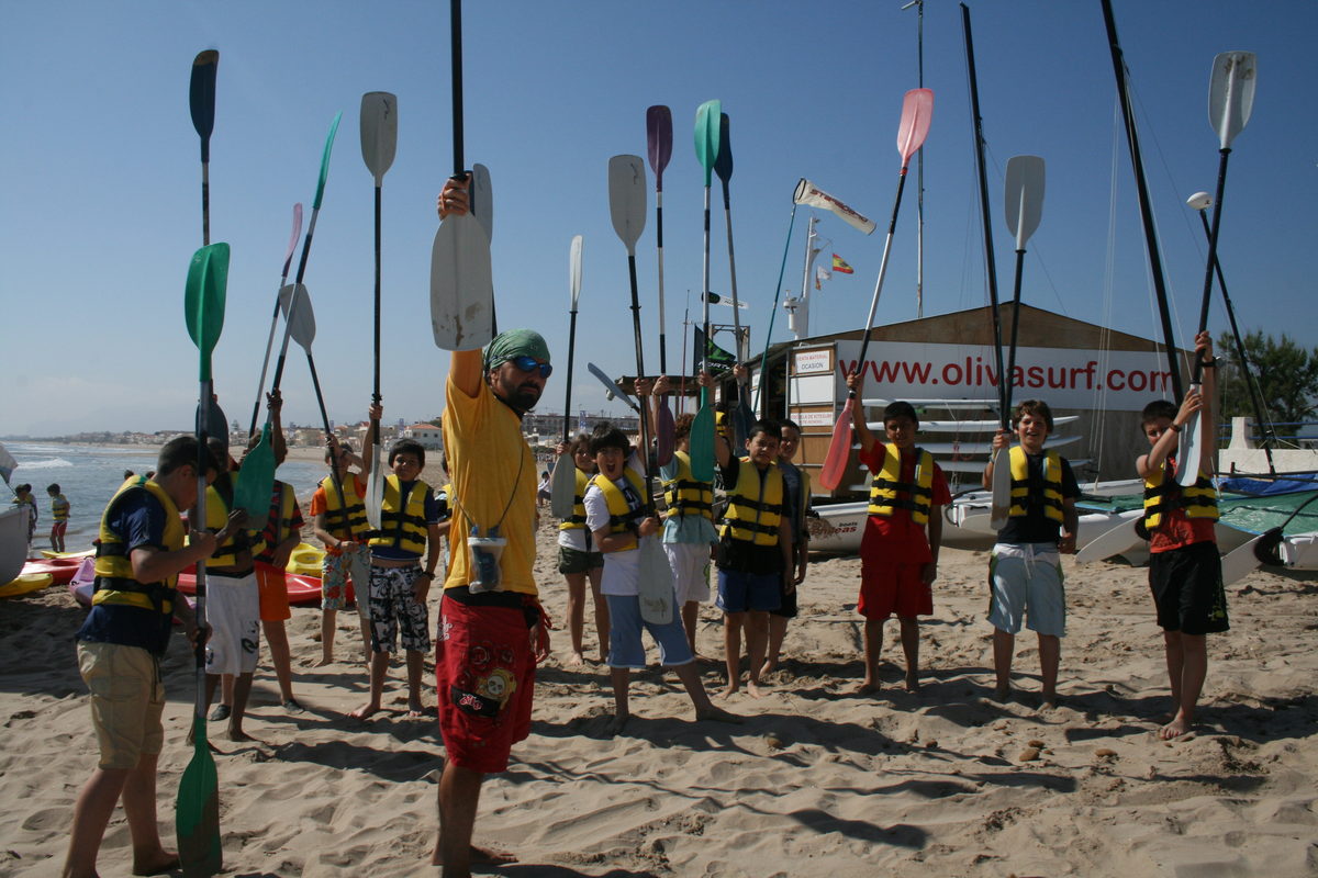 Grupo de campistas levantando las palas de piragua delante de la base náutica de Oliva Surf