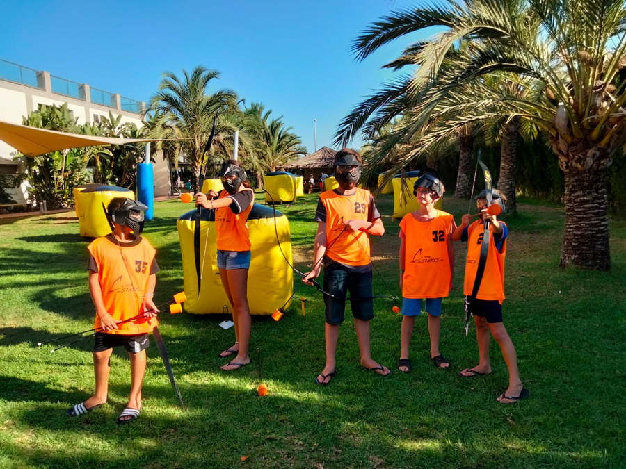 Partida de Archery Tag en el jardín, con petos naranjas y arcos