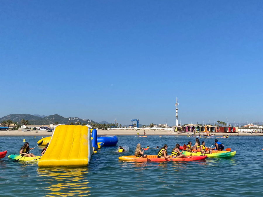 Parque acuático hinchable en el mar con campistas subiendo por el tobogán